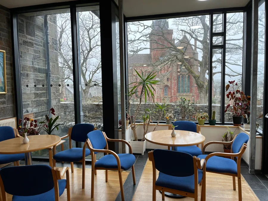 Tables and chairs in a bright room with a view of a red sandstone cathedral